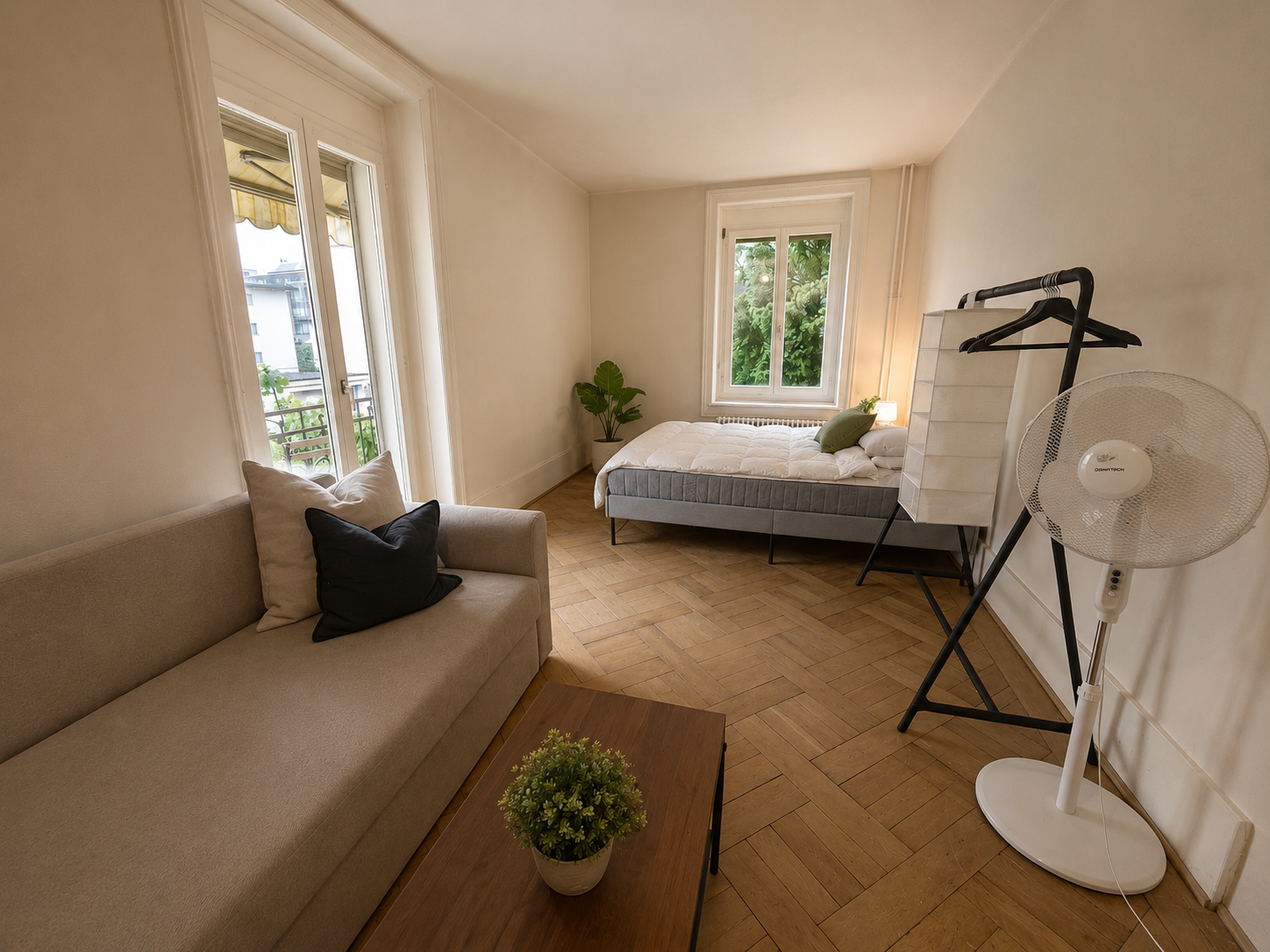 Möbliertes Studio mit Sofa, Bett und Balkon der Zwischennutzungswohnung Grundstrasse 1 in Zürich